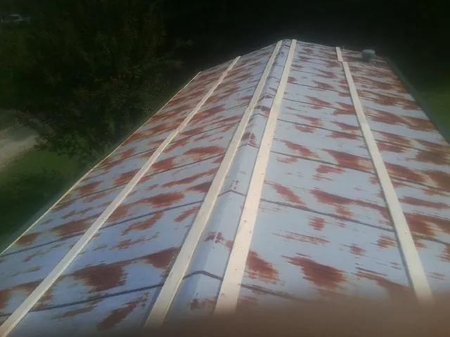 Rusted metal roof panels with new wood purlins before replacement — Storm Damage Roof Repair in Portis by Roofing Brothers