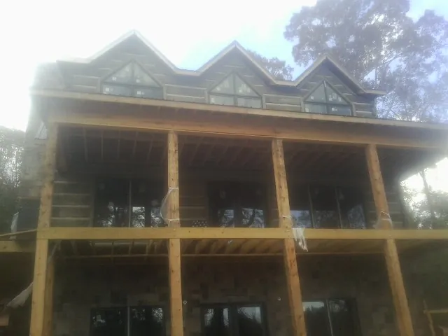 Dormers and porch framing on a large log home under construction — Roof Coating work by our crew in Portis