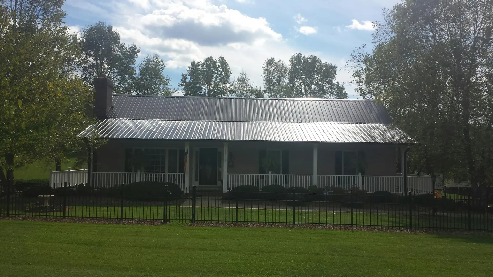 Gray metal roof on a brick ranch with a full width front porch — Gutter Guard Installation work by our crew in Portis