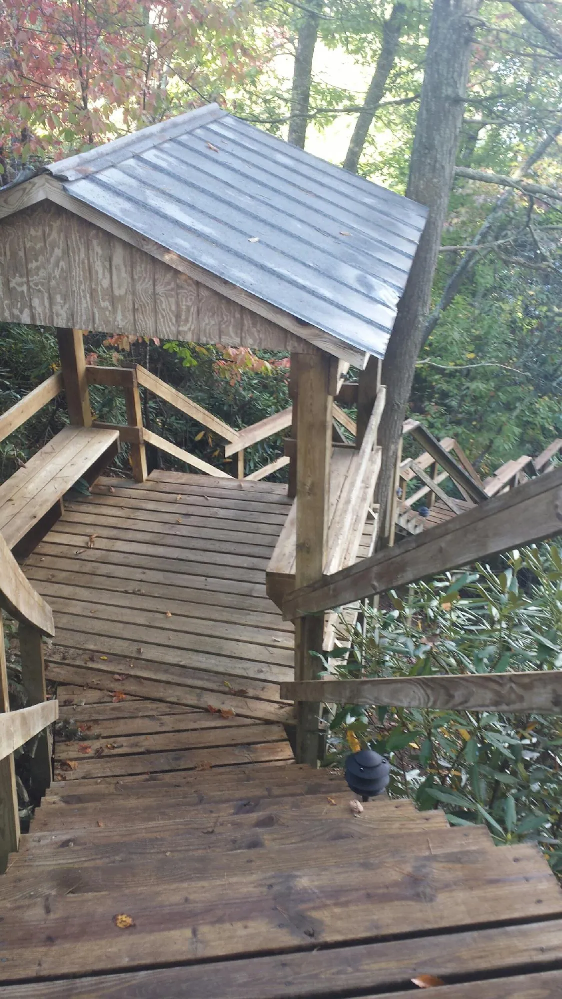 Metal roofed shelter over wooden steps on a wooded walkway — Skylight Repair & Installation work by our crew in Portis