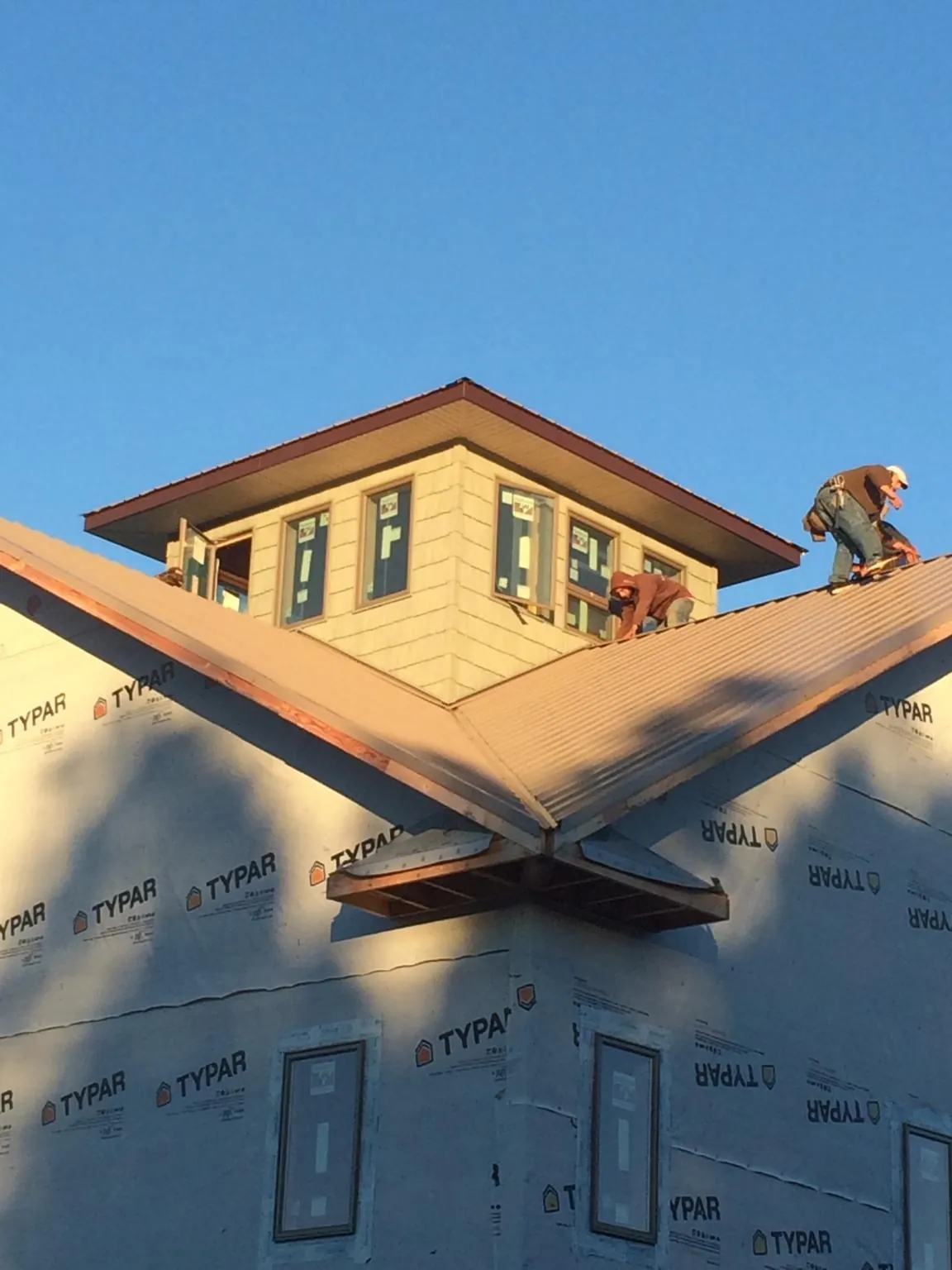 Roofers working around a rooftop cupola on a new metal roof at sunset — Roof Waterproofing in Portis by Roofing Brothers